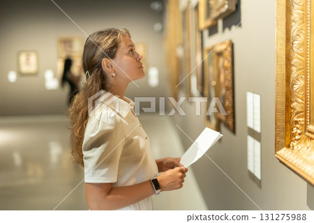 Woman with sheet piece of paper in hands view pictures and icons in museum hall 131275988
