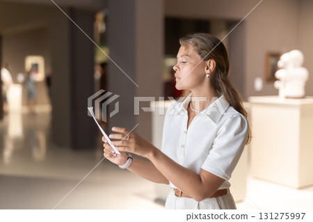 Portrait of attractive woman visiting sculpture hall in historical museum and looking at exhibits Portrait of attractive woman visiting sculpture hall in historical museum and looking at exhibits 131275997