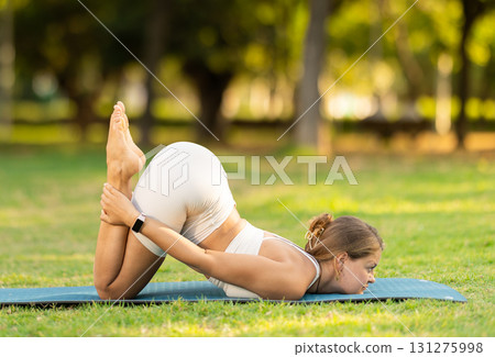 Girl enjoying outdoor yoga practice in green summer park Girl enjoying outdoor yoga practice in green summer park 131275998