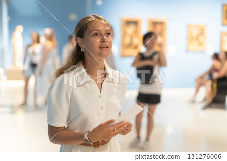 Woman with sheet piece of paper in hands view pictures and icons in museum hall 131276006