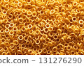 Dive into the whimsical world of pasta with this mesmerizing close-up shot of golden ring-shaped pasta. 131276290
