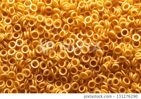 Dive into the whimsical world of pasta with this mesmerizing close-up shot of golden ring-shaped pasta. 131276290