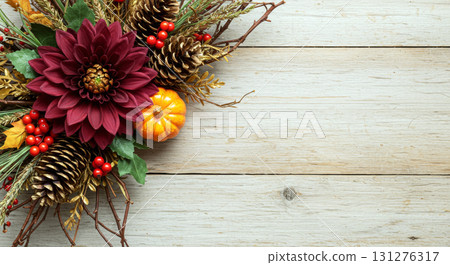 Rustic autumn floral and harvest composition with a dahlia, pinecones, and pumpkin on a whitewashed wood background. 131276317