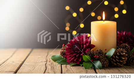 Burning candle with pinecones and dahlia flowers on a rustic wood table with dark, glowing bokeh. 131276320