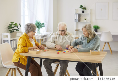 Group of three elderly women and man collecting mosaic, putting geometric shapes together Group of three elderly women and man collecting mosaic, putting geometric shapes together 131276536