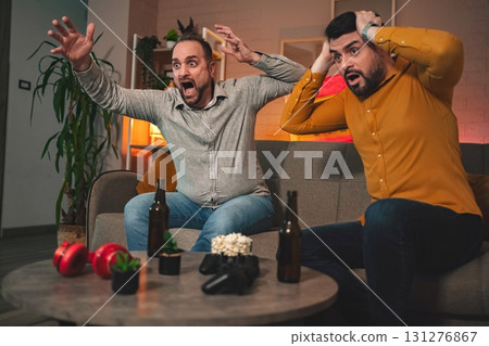 Friends share an intense moment as they react to a surprising plot twist while enjoying a gaming night at home 131276867