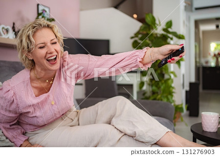 Woman laughing watching television with remote control 131276903