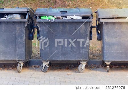 Dumpsters being full with garbage. Garbage, waste lots, junk dump. Trash cans. 131276976