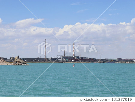 Azure waters of Lake Balkhash, Kazakhstan with a metallurgical plant in the background 131277019