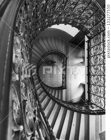 Spiral staircase with ornate wrought iron railing in black and white interior of grand historic building Spiral staircase with ornate wrought iron railing in black and white interior of grand historic building 131277550