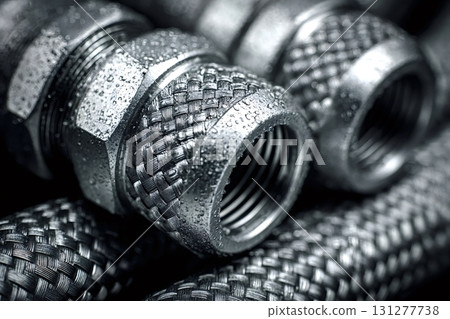 Plumbing hoses and fittings showing braided steel and water droplets 131277738