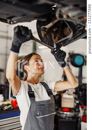 A woman is engaged in auto maintenance work in a wellequipped garage, showcasing her skills 131277898