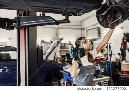 A mechanic is working on a vehicle in an auto shop, ensuring its functionality and safety A mechanic is working on a vehicle in an auto shop, ensuring its functionality and safety 131277900