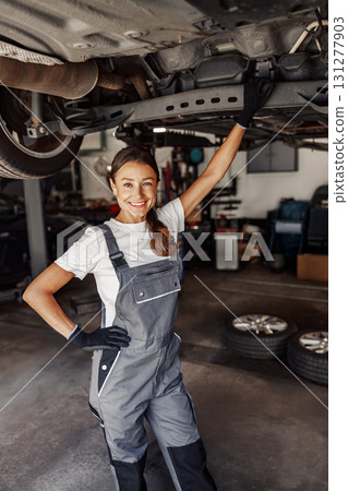 A Confident Female Mechanic Proudly Working in a Busy Garage, Demonstrating Her Skills and Expertise A Confident Female Mechanic Proudly Working in a Busy Garage, Demonstrating Her Skills and Expertise 131277903