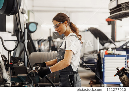 A skilled female mechanic diligently working in an automotive garage environment 131277910