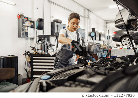 A female mechanic diligently working on a car in a modern and wellequipped auto shop setting 131277926