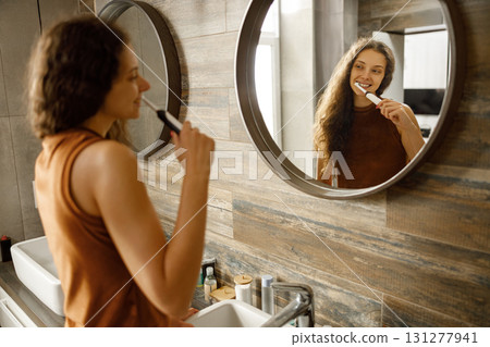 Morning Routine A Woman Brushing Her Teeth in a Beautiful, Modern Bathroom Space 131277941