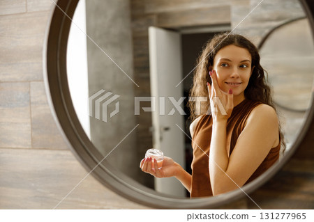 A woman applies cream in a stylish modern bathroom, highlighting her beauty routine and selfcare A woman applies cream in a stylish modern bathroom, highlighting her beauty routine and selfcare 131277965