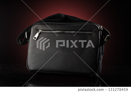 This black bag mockup showcases a sleek design featuring a prominent zipper pocket. The dark red background enhances its stylish appearance ideal for advertising or design presentations. This black bag mockup showcases a sleek design featuring a prominent zipper pocket. The dark red background enhances its stylish appearance ideal for advertising or design presentations. 131278459