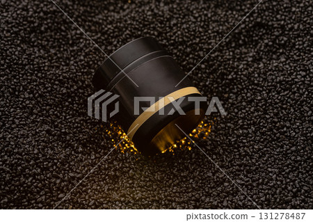 Black container with gold band rests on a textured black surface. This elegant mockup highlights the sleek design suitable for cosmetics. Ideal for branding or promotional purposes. 131278487