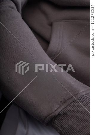 athletic man in a gray hoodie is getting ready for his workout in a gym during early morning. He focuses on his routine with determination and energy. 131278534