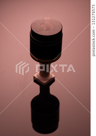 cosmetics mockup features a stylish black and gray container positioned on a reflective surface. Soft lighting creates a warm atmosphere enhancing the product's appeal. 131278573