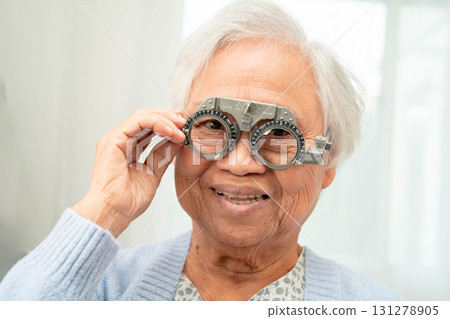 Optometrist checking Asian elderly woman ophthalmic vision eye test and using optical trial frame. Optometrist checking Asian elderly woman ophthalmic vision eye test and using optical trial frame. 131278905