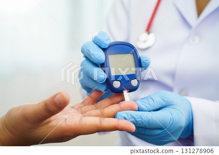Asian doctor using digital glucose meter for check sample blood sugar level to treatment diabetes. 131278906