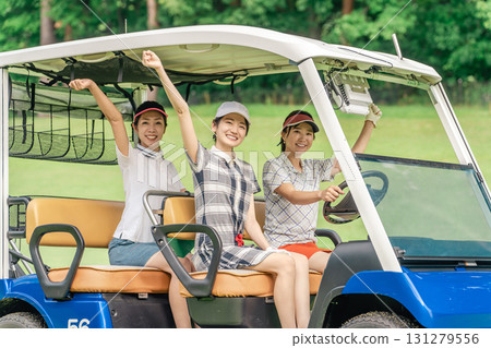 A golfer woman riding a golf cart on a golf course (golf girl) 131279556