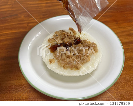 將醬油膏從塑膠袋裡倒入碗粿中 131279569
