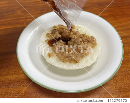 將醬油膏從塑膠袋裡倒入碗粿中 131279570
