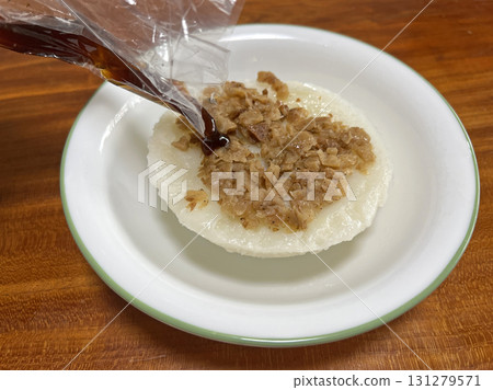 Pour the soy sauce paste from the plastic bag into the rice cake Pour the soy sauce paste from the plastic bag into the rice cake 131279571