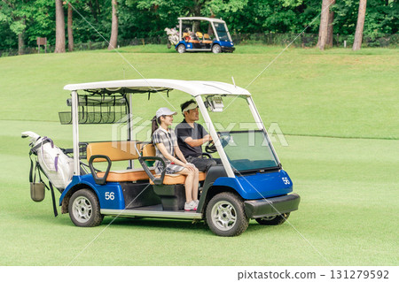 打高爾夫球的男人和女人在高爾夫球場上騎著高爾夫球車 打高爾夫球的男人和女人在高爾夫球場上騎著高爾夫球車 131279592