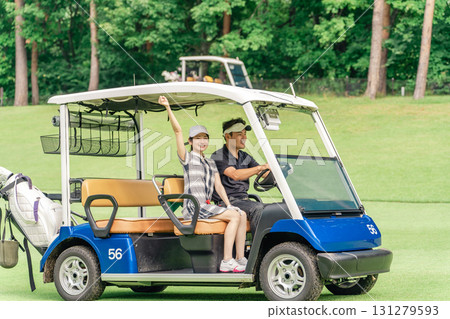打高爾夫球的男人和女人在高爾夫球場上騎著高爾夫球車 打高爾夫球的男人和女人在高爾夫球場上騎著高爾夫球車 131279593