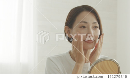 一位 40 多歲的日本女性對著鏡子檢查自己的皮膚狀況 一位 40 多歲的日本女性對著鏡子檢查自己的皮膚狀況 131279846