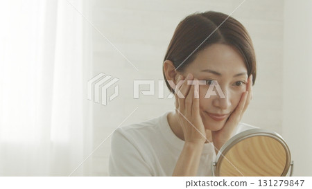 A Japanese woman in her 40s checking her skin condition in the mirror A Japanese woman in her 40s checking her skin condition in the mirror 131279847