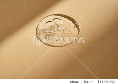 A drop of serum on a beige background. 131280899