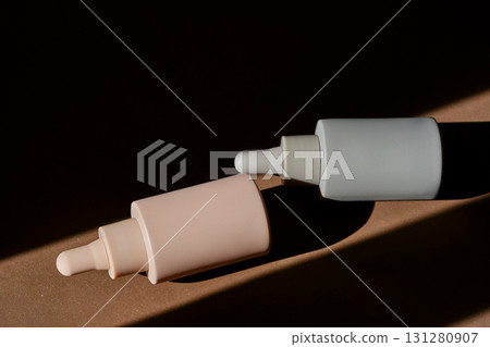 Two bottles of facial serum on a brown background. 131280907