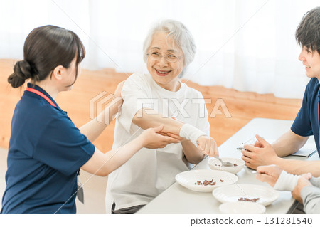 A senior woman and a female occupational therapist are undergoing functional training using a spoon at a care facility, where they are eating. 131281540
