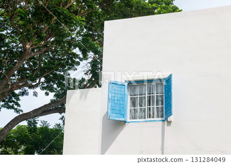 Blue wooden open shutters of window on white modern building 131284049