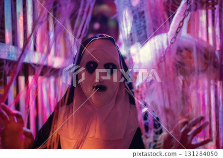 Spooky woman with devilish nun mask and dress in cage 131284050