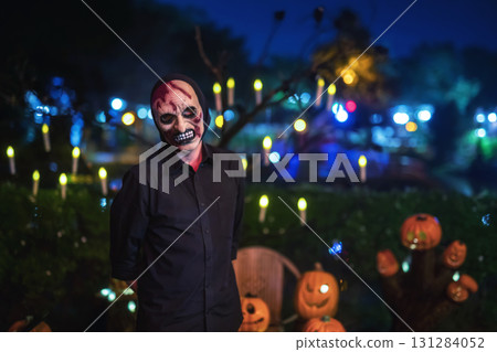 Scary man with devil mask stand by pumpkin in park, Halloween 131284052