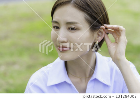 特寫鏡頭：一位年輕女子坐在公園裡，用手撫摸頭髮 131284302