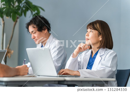 身穿白大褂的男女醫生坐在辦公桌前工作 身穿白大褂的男女醫生坐在辦公桌前工作 131284330