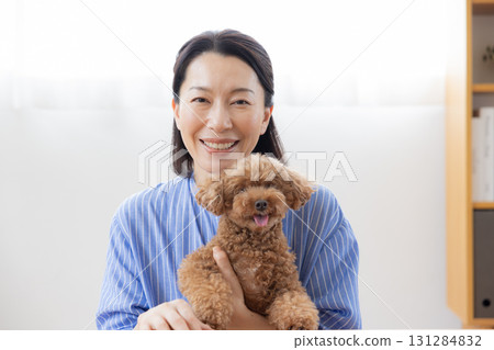 Remote meeting: Middle-aged woman holding a dog and talking to the camera Remote meeting: Middle-aged woman holding a dog and talking to the camera 131284832