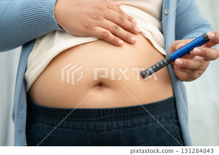 Asian woman injecting herself diabetes injecting insulin in stomach at home. Asian woman injecting herself diabetes injecting insulin in stomach at home. 131284843