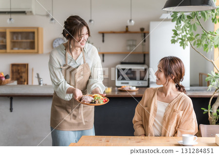 A cafe staff member serves a one-plate lunch, explains the dishes, and a female customer 131284851