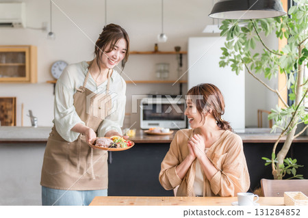 A cafe staff member serves a one-plate lunch, explains the dishes, and a female customer 131284852