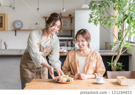 A cafe staff member serves a one-plate lunch, explains the dishes, and a female customer 131284853