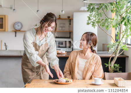 A cafe staff member serves a one-plate lunch, explains the dishes, and a female customer 131284854
